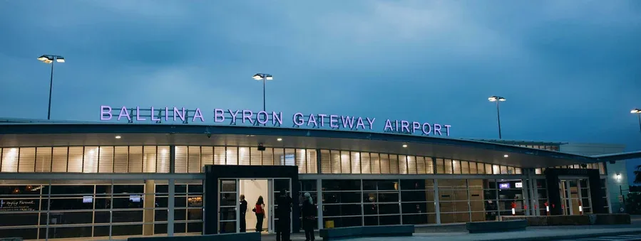 The Ballina Byron Gateway Airport terminal at dusk, its illuminated name sign glowing above the entrance.