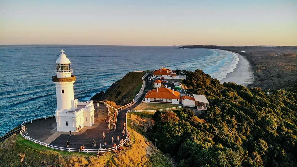 Cape Byron lighthouse at golden hour with Tallow Beach stretching into the distance